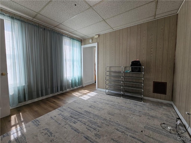 interior space with wooden walls, visible vents, a paneled ceiling, and wood finished floors