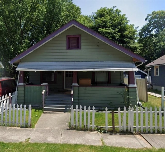 bungalow-style home with a porch, a fenced front yard, and a front yard