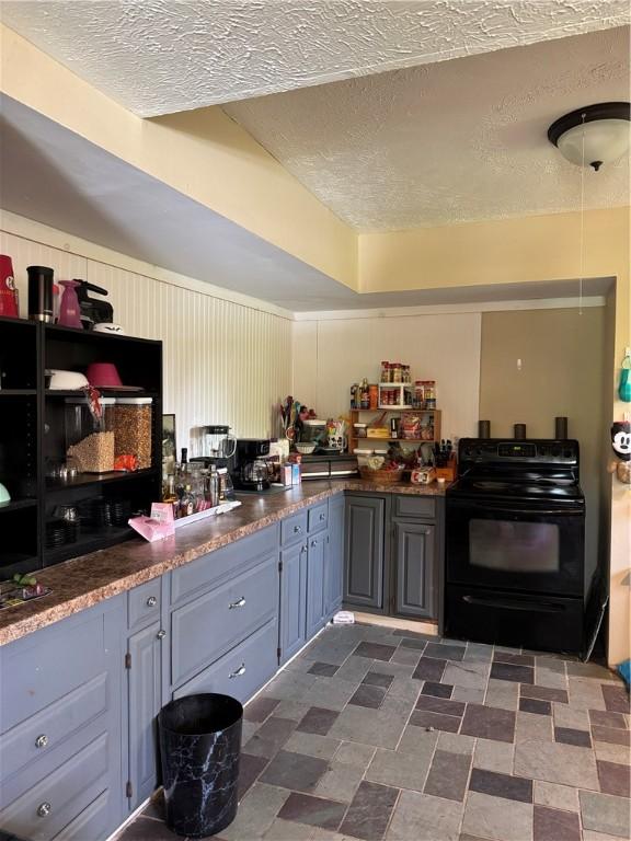 kitchen with a textured ceiling, dark countertops, and black electric range oven