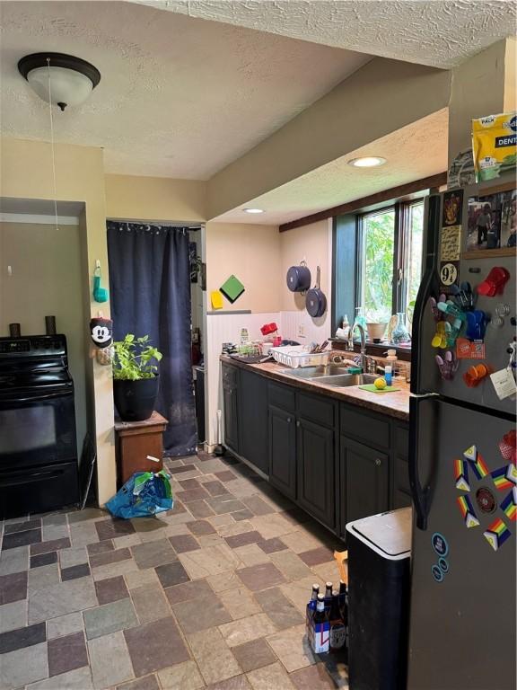 kitchen with a sink, dark cabinets, a textured ceiling, recessed lighting, and black appliances