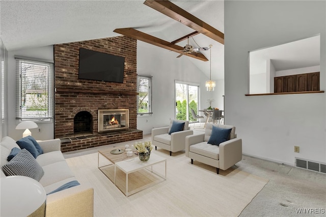 carpeted living room with vaulted ceiling with beams, a brick fireplace, visible vents, and ceiling fan
