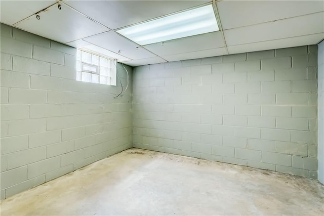 below grade area with a paneled ceiling and concrete block wall