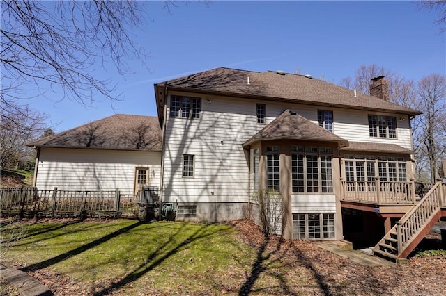 rear view of property featuring fence, stairs, a wooden deck, a chimney, and a yard