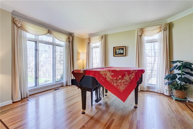 living area with baseboards, ornamental molding, wood finished floors, and visible vents