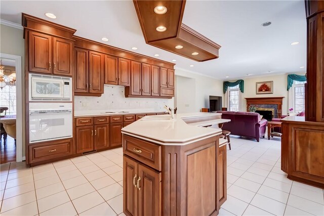 kitchen featuring light tile patterned floors, light countertops, brown cabinets, and white appliances