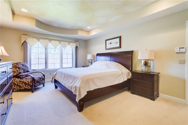 bedroom featuring recessed lighting, baseboards, light colored carpet, and a tray ceiling