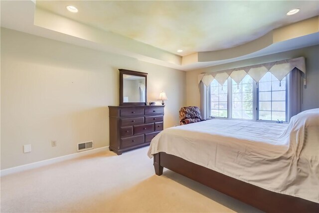 carpeted bedroom with recessed lighting, baseboards, visible vents, and a tray ceiling