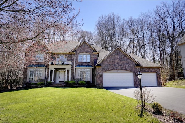 traditional-style house with driveway, a front yard, brick siding, a balcony, and an attached garage