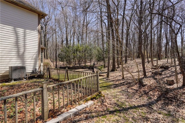 view of yard with central AC unit and fence
