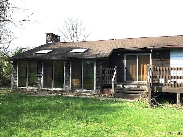 rear view of house with a lawn, a chimney, and a shingled roof