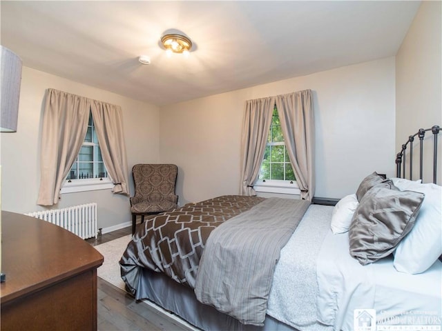 bedroom featuring radiator heating unit, baseboards, and dark wood finished floors