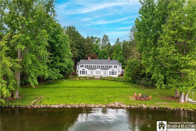 rear view of property with a lawn and a water view