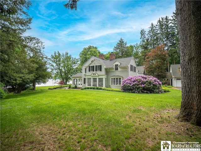 exterior space featuring a garage, a chimney, and a front lawn