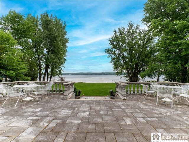 view of patio with a water view and outdoor dining space