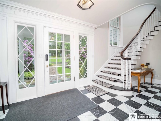 entryway with crown molding, stairs, and baseboards