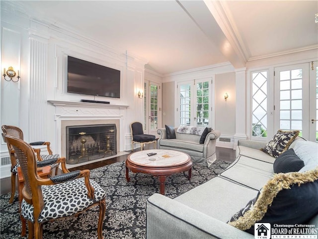 living room featuring beam ceiling, a fireplace with flush hearth, ornamental molding, and wood finished floors