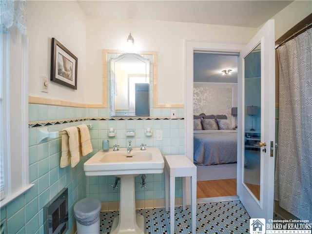 ensuite bathroom with a sink, tile walls, ensuite bathroom, and a wainscoted wall
