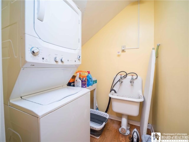 laundry area featuring stacked washer / drying machine and wood finished floors