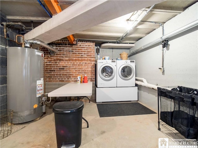 unfinished basement featuring washer and clothes dryer, gas water heater, and brick wall