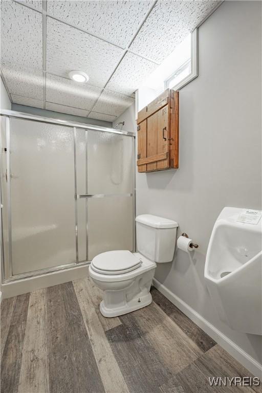 2575 Fuller Rd, Newfane, NY 14028 - bathroom featuring wood finished floors, toilet, baseboards, a paneled ceiling, and a shower stall