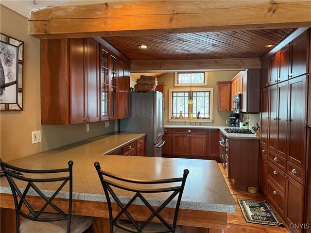 2321 Olanco Rd, Spafford, NY 13110 - kitchen featuring appliances with stainless steel finishes, wooden ceiling, a peninsula, wood finished floors, and glass insert cabinets