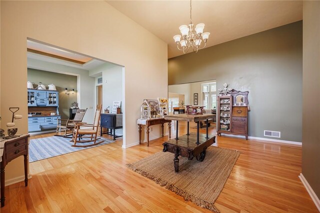 office space featuring a notable chandelier, visible vents, baseboards, and light wood-style floors