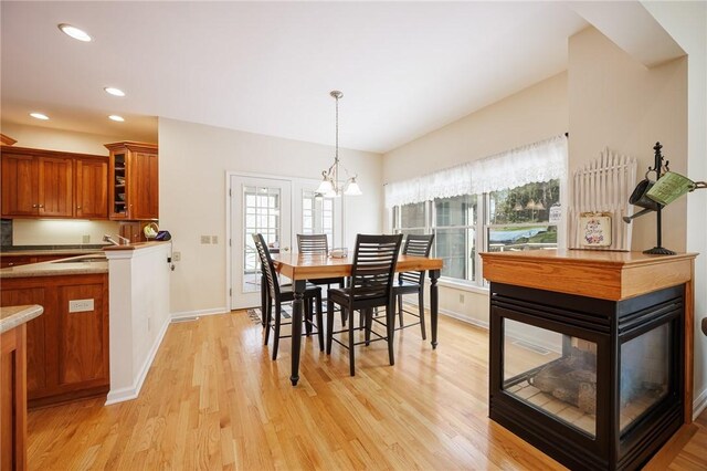 dining space featuring light wood-style floors, recessed lighting, baseboards, and a notable chandelier