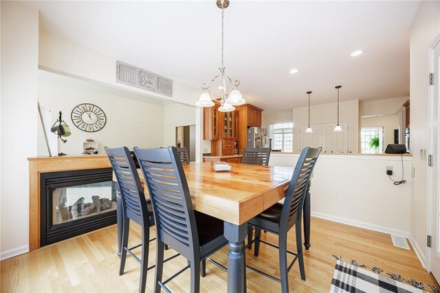 dining space featuring light wood-style floors, baseboards, recessed lighting, and a chandelier
