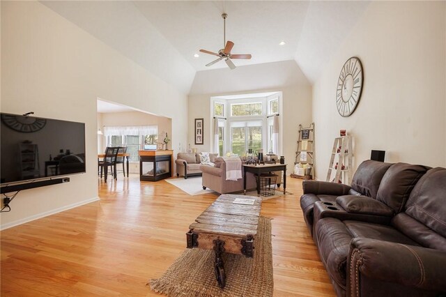 living area featuring a ceiling fan, high vaulted ceiling, and light wood-style floors