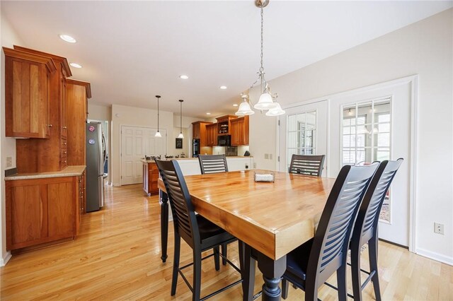 dining area with light wood-type flooring, recessed lighting, baseboards, and a notable chandelier