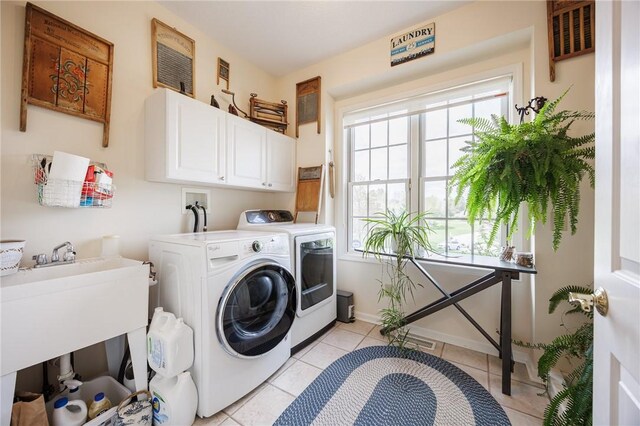 clothes washing area featuring visible vents, baseboards, washing machine and clothes dryer, cabinet space, and light tile patterned floors