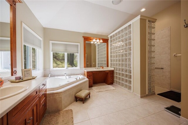 full bathroom featuring tile patterned flooring, walk in shower, a bath, two vanities, and a sink