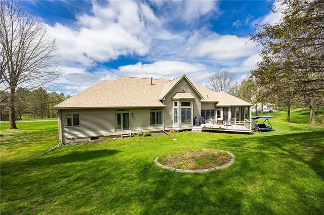 rear view of house featuring a lawn, roof with shingles, and a deck