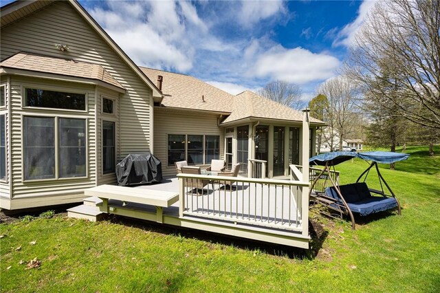 rear view of house with a lawn, a shingled roof, a sunroom, and a deck