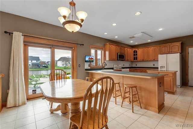 kitchen with light tile patterned flooring, a sink, white appliances, a peninsula, and glass insert cabinets