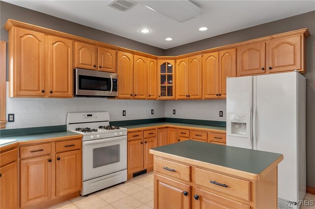 kitchen with white appliances, recessed lighting, light tile patterned floors, tasteful backsplash, and glass insert cabinets