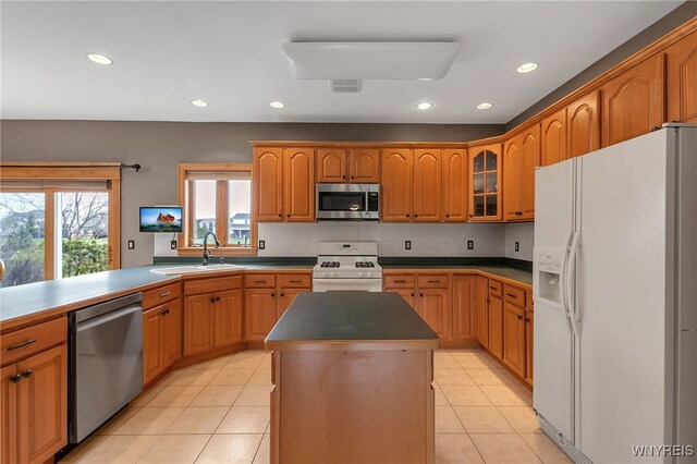 kitchen with a kitchen island, appliances with stainless steel finishes, a sink, recessed lighting, and light tile patterned flooring