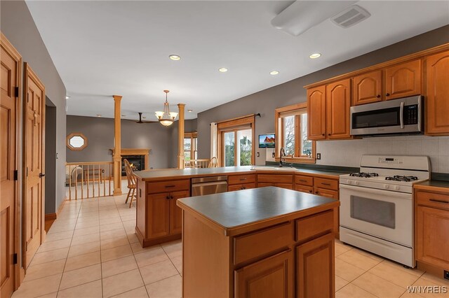 kitchen featuring visible vents, a peninsula, a sink, appliances with stainless steel finishes, and light tile patterned floors