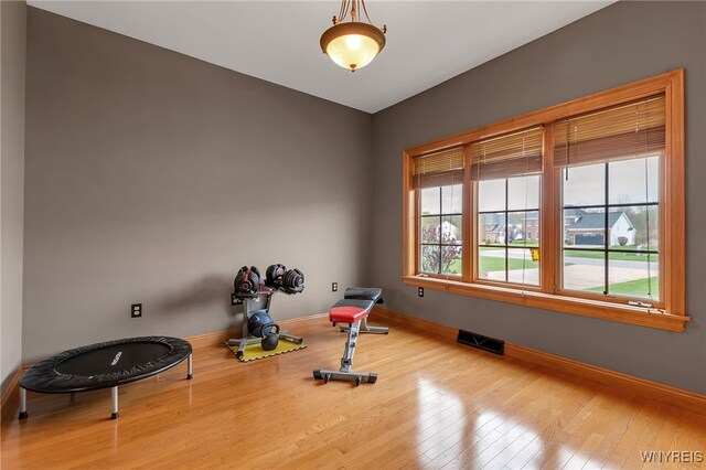 exercise room featuring visible vents, baseboards, and wood finished floors