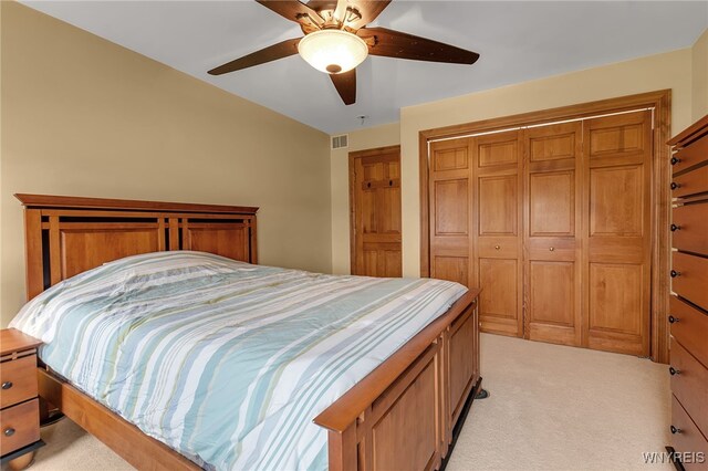 bedroom with a closet, light carpet, a ceiling fan, and visible vents