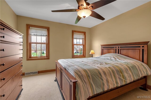 bedroom featuring baseboards, visible vents, a ceiling fan, and light colored carpet