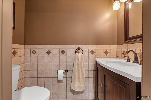 bathroom with toilet, tile walls, a wainscoted wall, and vanity