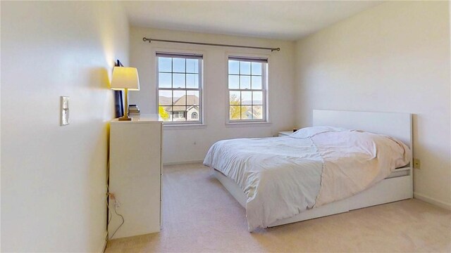 bedroom featuring light colored carpet and baseboards