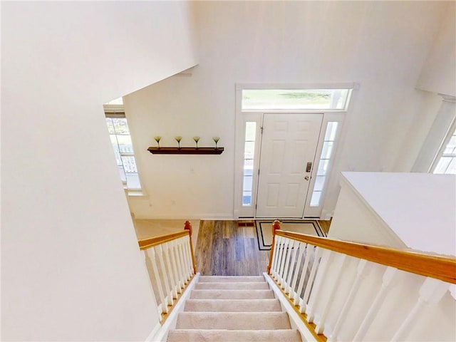 foyer entrance featuring baseboards, wood finished floors, a wealth of natural light, and stairway