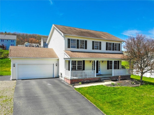 traditional-style home featuring a garage, covered porch, a front lawn, and aphalt driveway