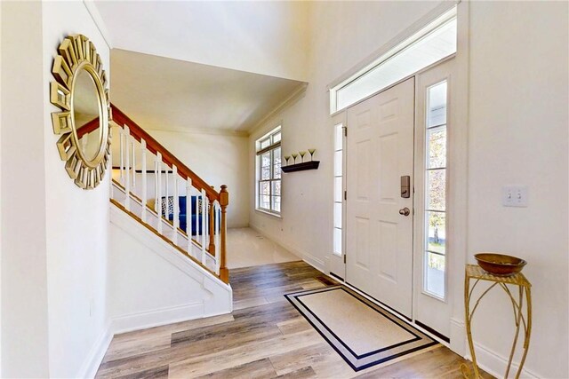 foyer entrance featuring stairway, baseboards, and wood finished floors