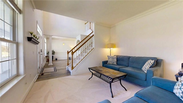 living room with decorative columns, crown molding, baseboards, carpet, and stairs