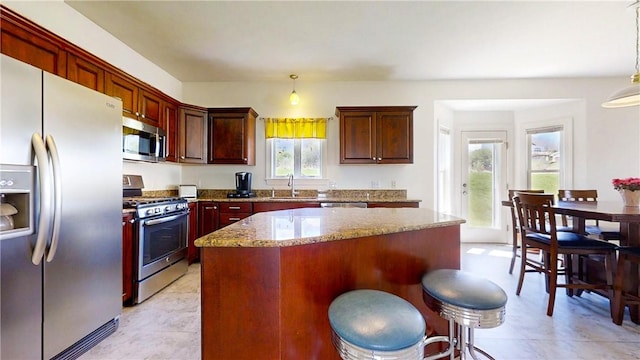 kitchen with a sink, appliances with stainless steel finishes, a center island, and pendant lighting