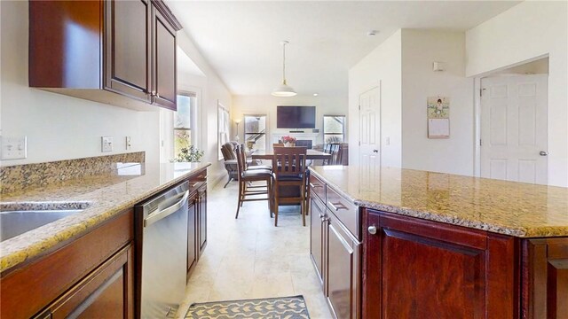 kitchen with a center island, decorative light fixtures, dishwasher, and light stone countertops