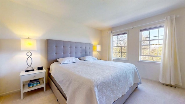 bedroom with baseboards, visible vents, and light carpet